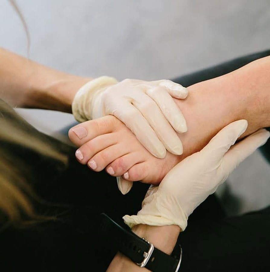 Två gummihandskar håller varsamt om en fot under behandling